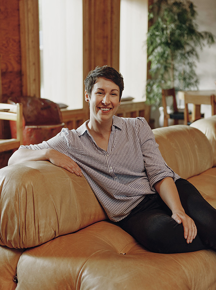 Kim Miller headshot, sitting on a leather couch